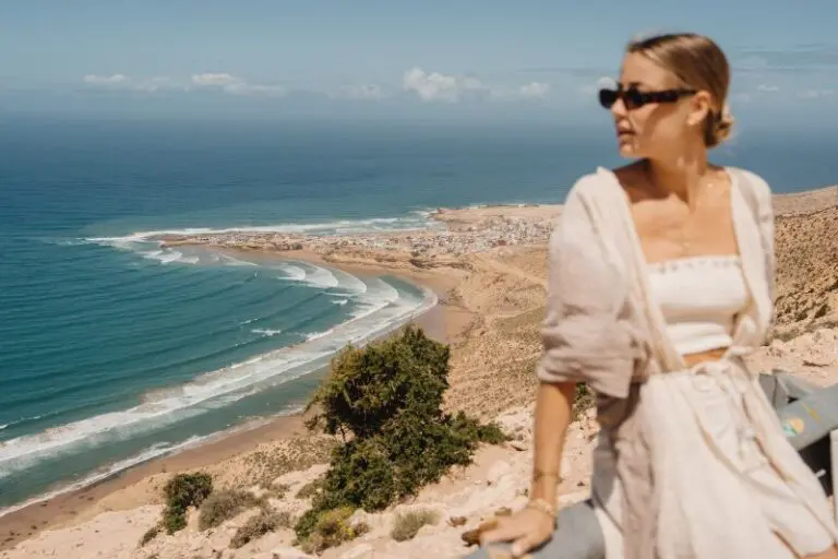 Frau, die vor einer Aussicht auf das Meer posiert.