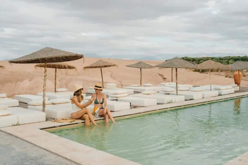 Frauen, die in einem Pool in der Wüste schwimmen.