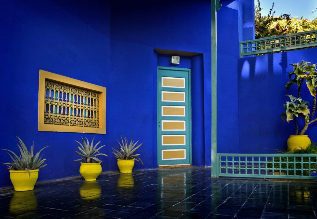 Foto van de Majorelle-tuinen in Marrakech met planten en blauwe muren.