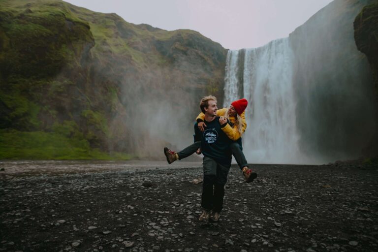 Zwei Personen vor einem Wasserfall in Island.